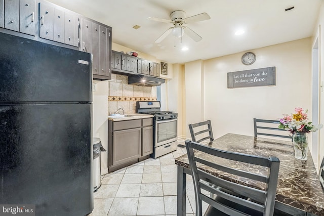 kitchen with tasteful backsplash, black fridge, ceiling fan, gas range, and light tile patterned floors