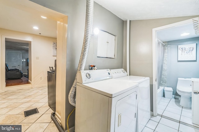 clothes washing area featuring washer and dryer and light tile patterned floors