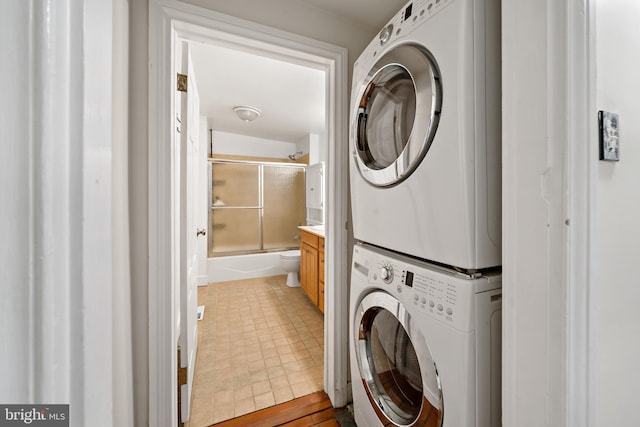 washroom with tile patterned flooring and stacked washing maching and dryer