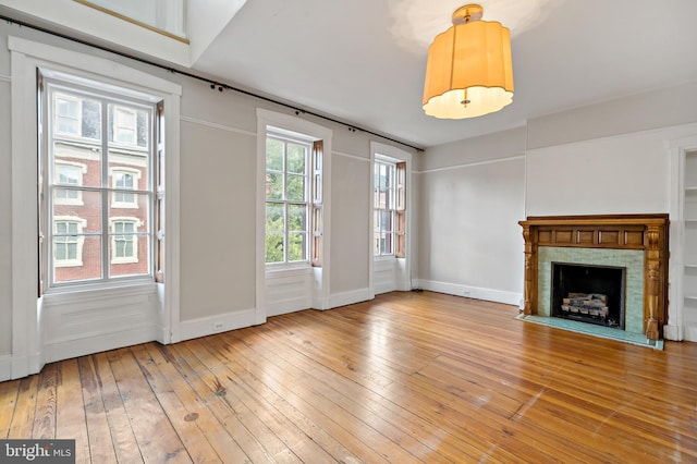 unfurnished living room featuring a tile fireplace and hardwood / wood-style floors