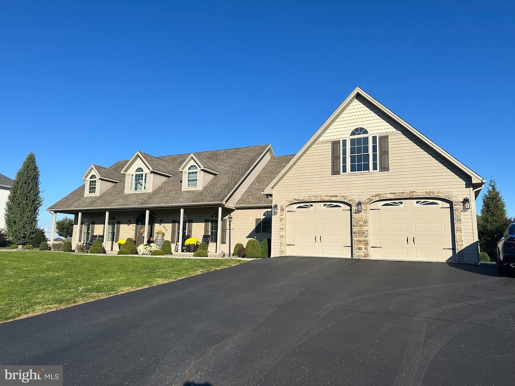 view of front of house with covered porch, a front yard, and a garage