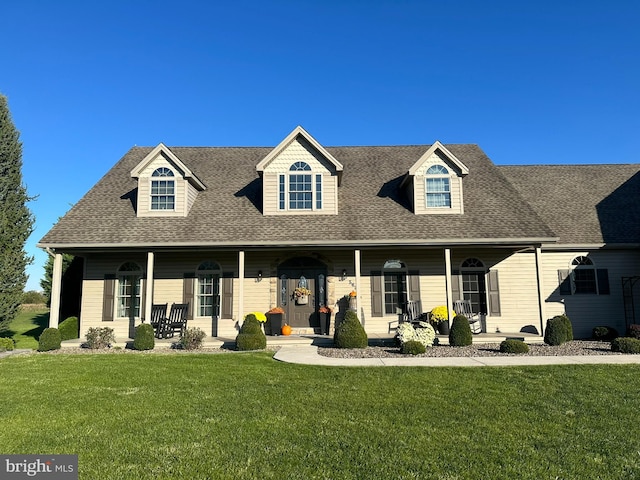 new england style home featuring a porch and a front lawn