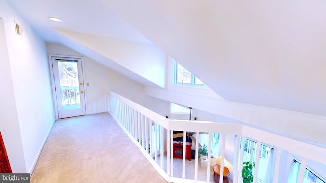 corridor with light colored carpet and vaulted ceiling