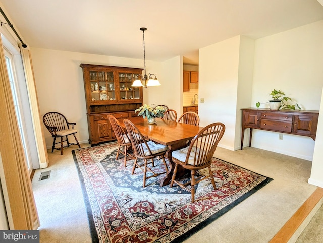 dining area featuring a notable chandelier and light carpet