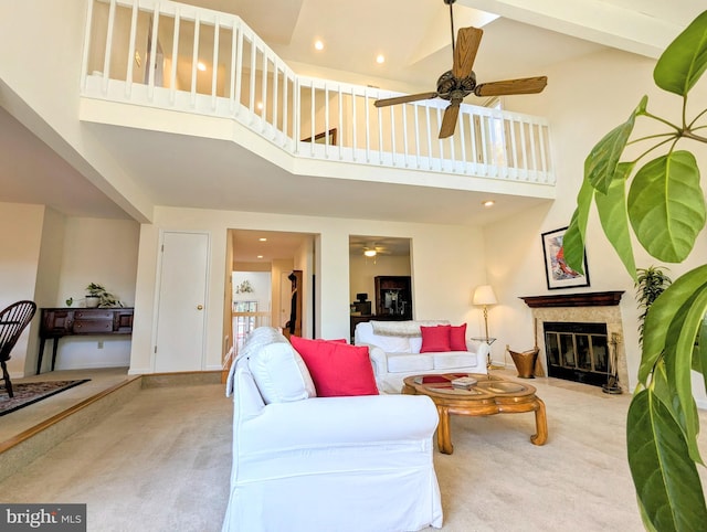 living room with a towering ceiling, ceiling fan, and light carpet