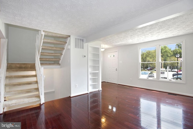 unfurnished living room featuring a textured ceiling and dark wood-type flooring