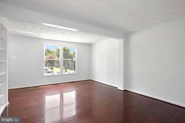 empty room with a textured ceiling and dark hardwood / wood-style flooring