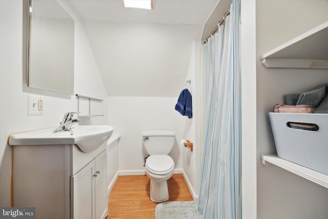 bathroom featuring lofted ceiling, toilet, wood-type flooring, curtained shower, and vanity