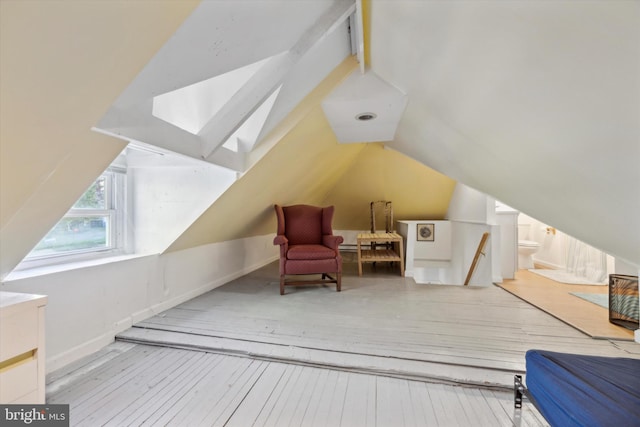 bonus room with lofted ceiling with skylight and light hardwood / wood-style flooring