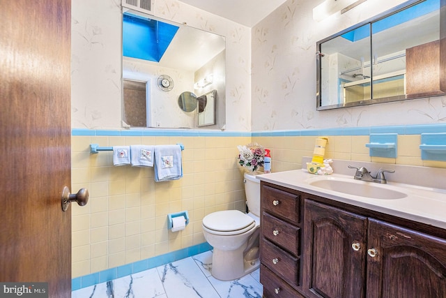 bathroom with vanity, tile walls, and toilet