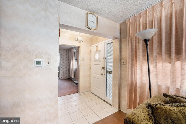 entryway with light tile patterned floors, a textured ceiling, and a notable chandelier