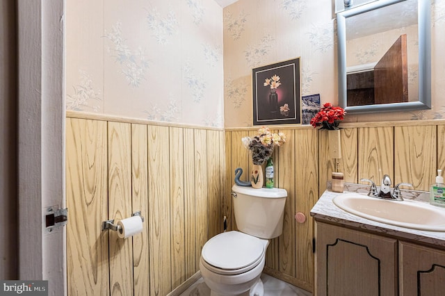 bathroom featuring wooden walls, vanity, and toilet