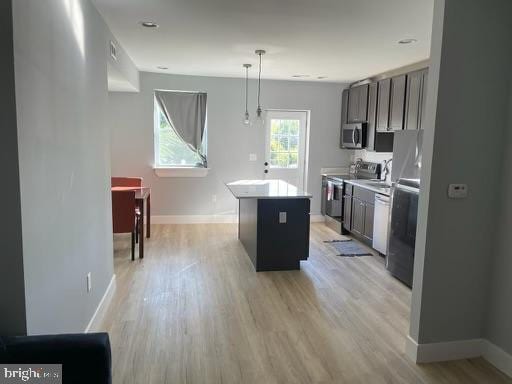 kitchen with light hardwood / wood-style flooring, stainless steel appliances, pendant lighting, and a center island