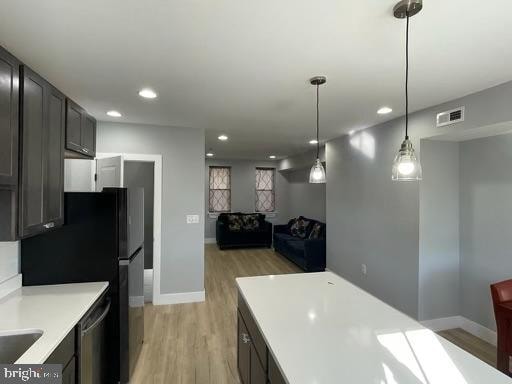 kitchen featuring decorative light fixtures, light wood-type flooring, and stainless steel dishwasher