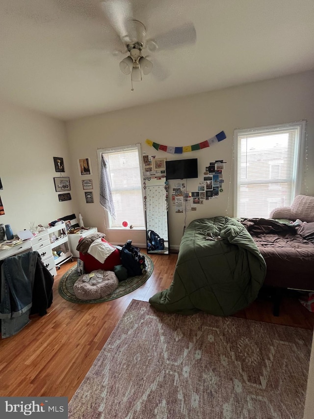 bedroom with multiple windows, wood-type flooring, and ceiling fan