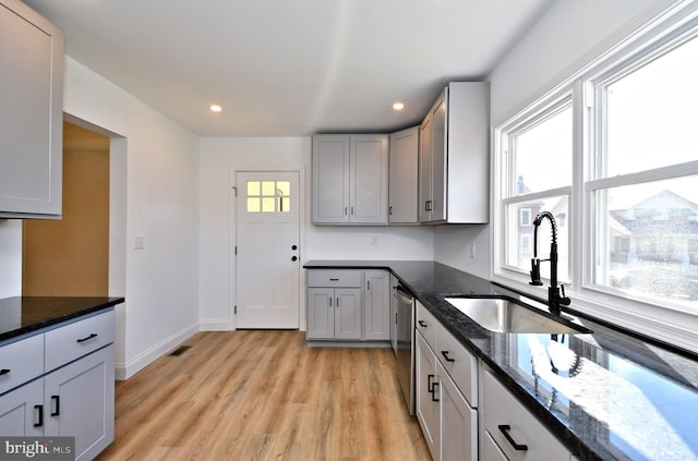 kitchen with gray cabinets, sink, light hardwood / wood-style flooring, and dark stone countertops