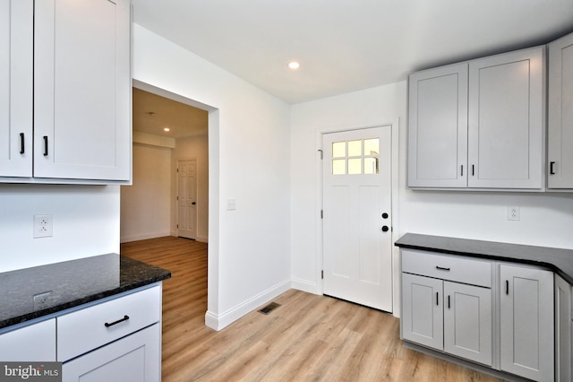 kitchen with light hardwood / wood-style floors and dark stone counters