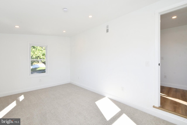 empty room featuring light colored carpet and vaulted ceiling