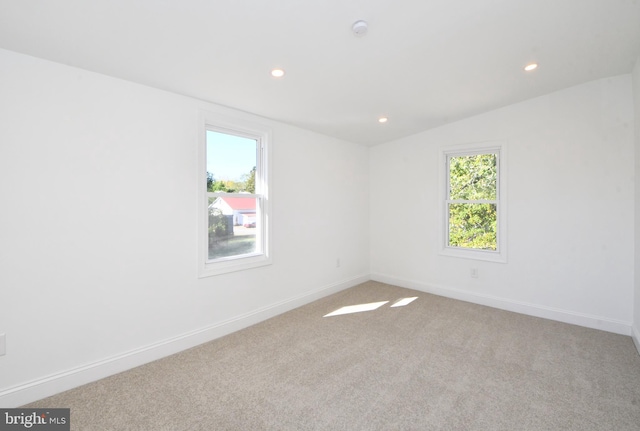 carpeted spare room with vaulted ceiling