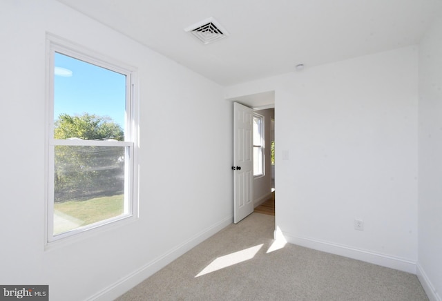 empty room with light colored carpet and a wealth of natural light