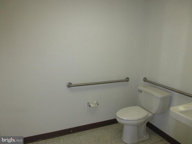 half bathroom with baseboards and toilet