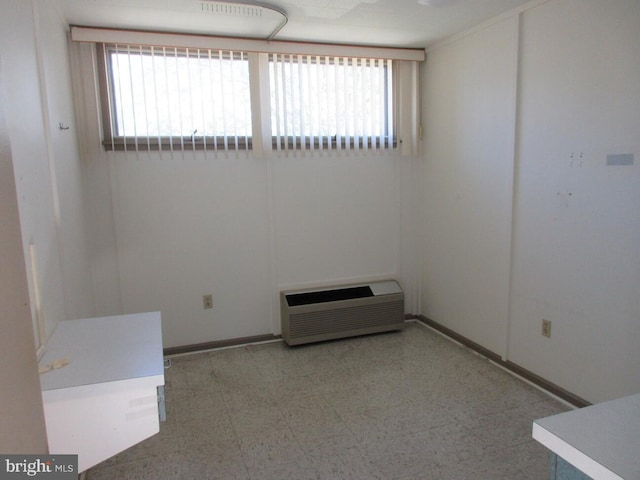 spare room with tile patterned floors, baseboards, and a wall mounted air conditioner