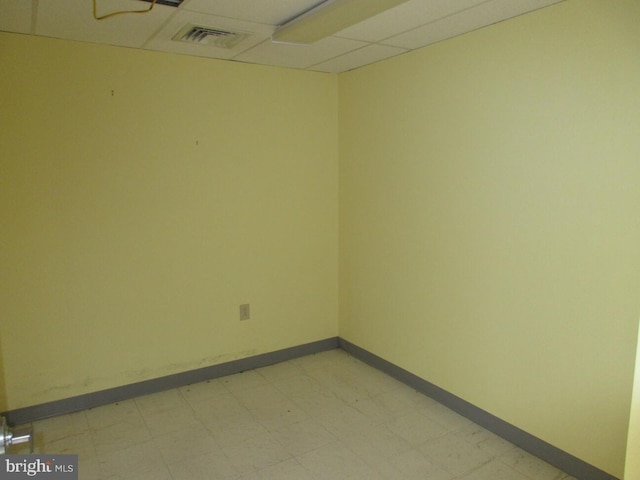 spare room featuring visible vents, baseboards, a paneled ceiling, and light floors