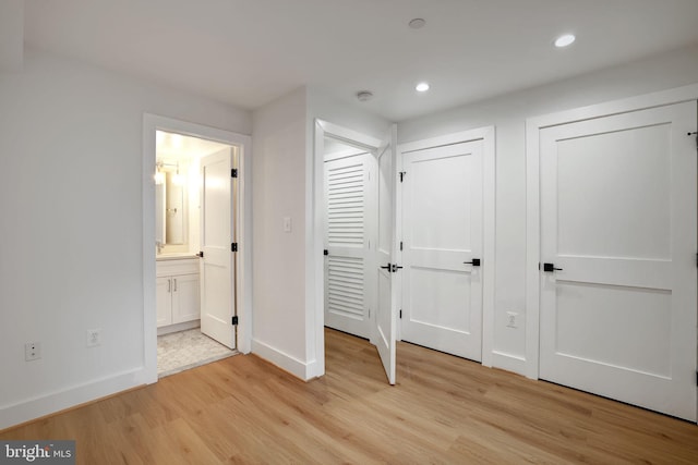 unfurnished bedroom featuring connected bathroom and light hardwood / wood-style floors