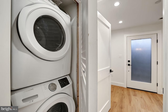 clothes washing area with stacked washer and clothes dryer and light hardwood / wood-style flooring