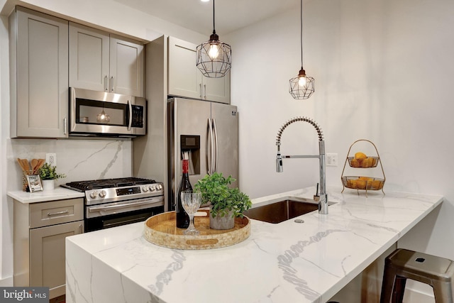 kitchen featuring light stone counters, stainless steel appliances, tasteful backsplash, sink, and hanging light fixtures