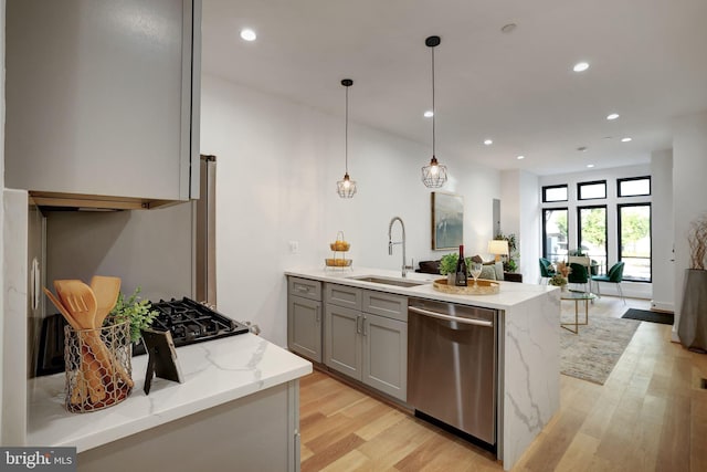 kitchen with pendant lighting, light hardwood / wood-style flooring, sink, light stone countertops, and stainless steel dishwasher