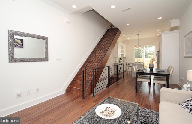 living room with ornamental molding, a notable chandelier, and dark wood-type flooring