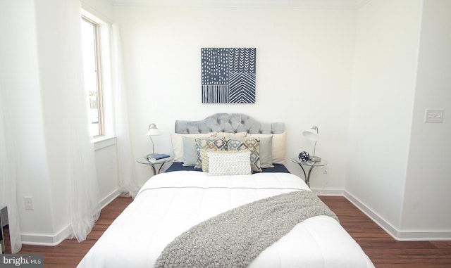 bedroom featuring ornamental molding, dark wood-type flooring, and multiple windows