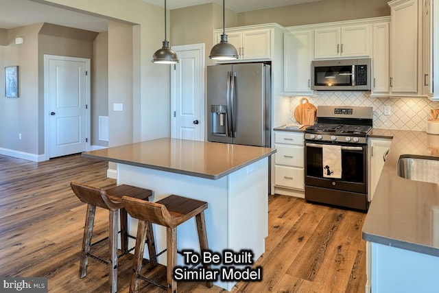 kitchen with a kitchen bar, appliances with stainless steel finishes, light wood-type flooring, a kitchen island, and white cabinetry