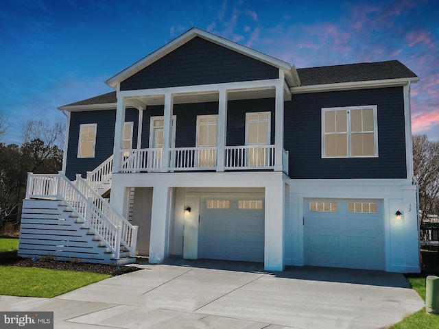 view of front of property featuring a porch, an attached garage, driveway, and stairway