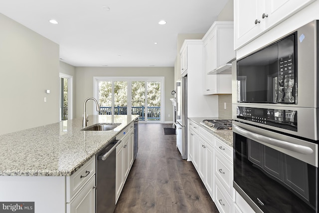 kitchen with white cabinets, sink, a center island with sink, dark wood-type flooring, and appliances with stainless steel finishes