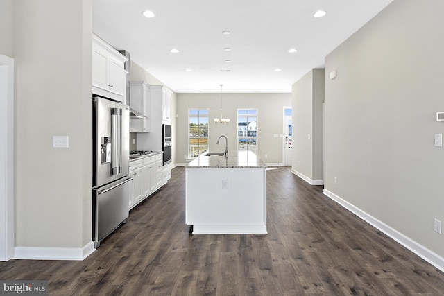 kitchen featuring sink, stainless steel appliances, hanging light fixtures, white cabinets, and an island with sink