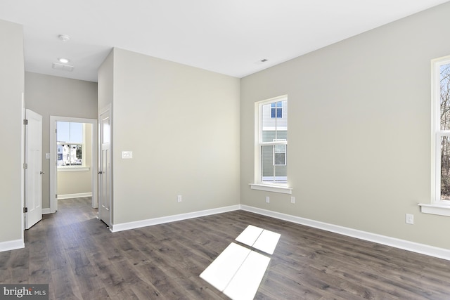 unfurnished room featuring dark wood-type flooring, baseboards, and plenty of natural light