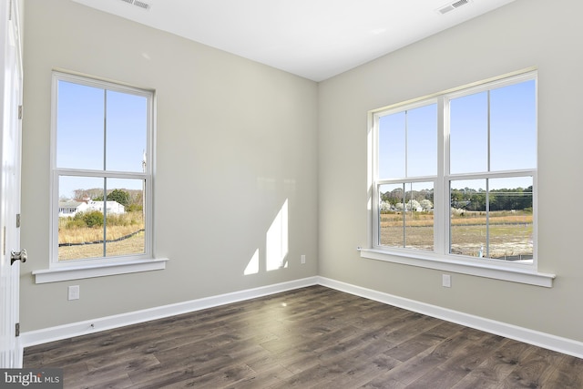 spare room featuring baseboards, dark wood finished floors, and visible vents