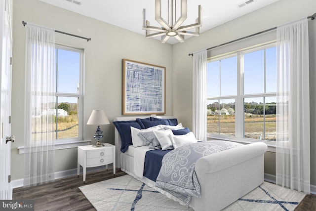 bedroom featuring hardwood / wood-style floors, an inviting chandelier, and multiple windows