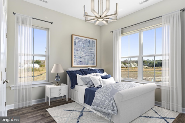 bedroom featuring visible vents, baseboards, an inviting chandelier, and wood finished floors