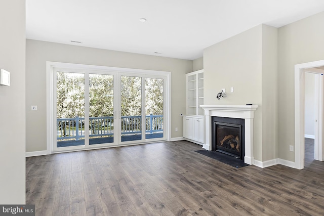 unfurnished living room with a fireplace with flush hearth, dark wood-style flooring, and baseboards