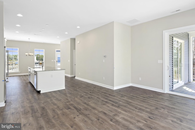 kitchen featuring a center island with sink, decorative light fixtures, sink, and dark wood-type flooring