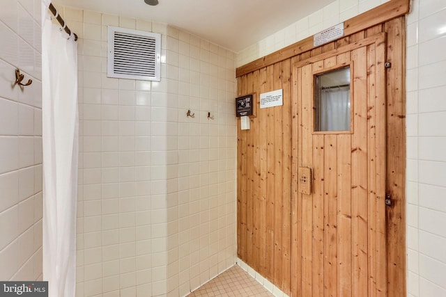 bathroom featuring a shower with shower curtain, tile patterned floors, and wooden walls