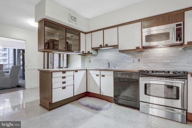 kitchen featuring white cabinetry, stainless steel appliances, tasteful backsplash, and a sink