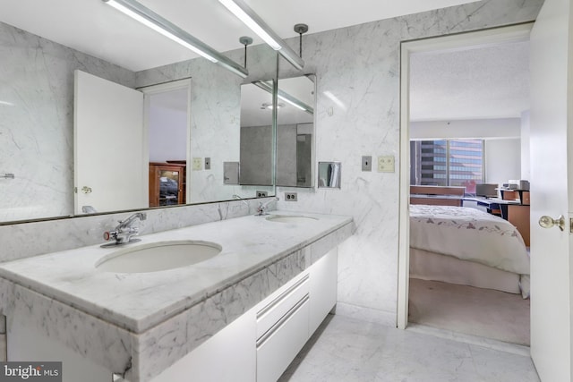 full bathroom with double vanity, ensuite bathroom, marble finish floor, and a sink