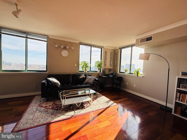 living room featuring dark wood-type flooring, ornamental molding, rail lighting, and a textured ceiling