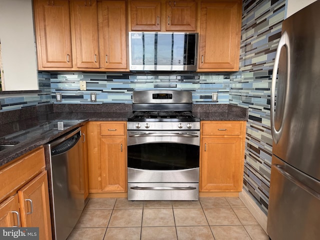 kitchen featuring appliances with stainless steel finishes, dark stone countertops, and light tile patterned floors