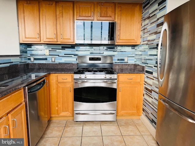 kitchen with tasteful backsplash, appliances with stainless steel finishes, dark stone countertops, and light tile patterned floors