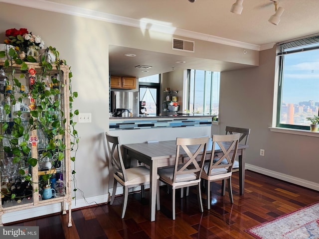 dining area featuring a healthy amount of sunlight, track lighting, ornamental molding, and dark hardwood / wood-style flooring